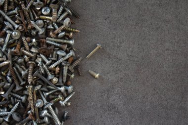 Eski civatalar ve fındıklar koyu gri beton arka planda. Çerçeve ya da sınır. Kopyalama alanı olan desenli arkaplan. 