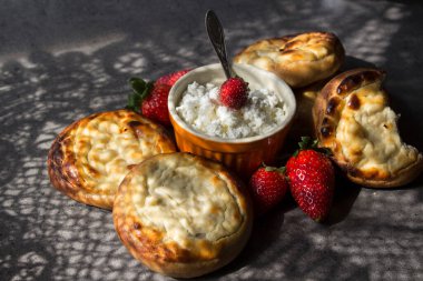 Geleneksel Rus hamur işleri Vatrushka gri dokulu arka planda. Masadaki dantel perdelerin güzel gölgeleri. Kır evi manzaralı tatlı çörekler.