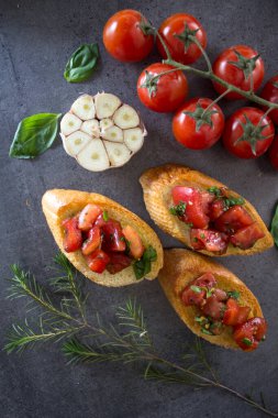 Lezzetli bruschetta, kızarmış domates ve fesleğen. Kızarmış ekmek ve taze sebzelerin yakın plan fotoğrafını çek. Otantik İtalyan yemekleri. 
