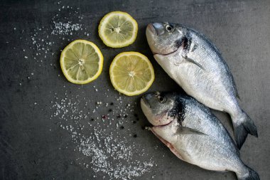Limonlu ve tuzlu deniz kepekli dorado balığı. Gri desenli arka planda fotokopi alanı var. Pişmemiş balık manzaralı fotoğraf. Dengeli diyet kavramı. 