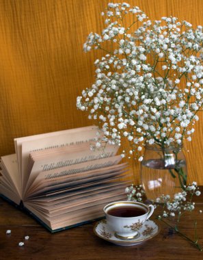 Bir fincan çayla sakin bir hayat. Üzerinde küçük beyaz çiçekler ve bir fincan siyah çay olan basit kompozisyon fotoğrafı. Güzel sabah resmi..