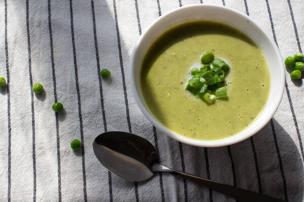 Закрыть фотографию вегетарианского супа в миске. Зеленый гороховый сливочный суп с луком. Концепция здорового питания. 