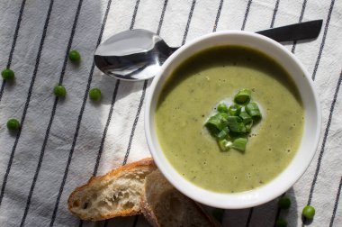 Taze baget ekmeği ve gümüş kaşıkla bezelyeden yapılmış kremalı çorba. Dengeli diyet konsepti. Lezzetli vejetaryen çorbasının en iyi fotoğrafı.. 