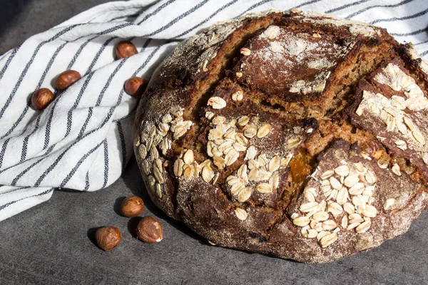 Round rye sourdough bread on striped kitchen towel. Close up photo of  healthy homemade bread with nuts. Eating healthy concept. Artisan bread top view.