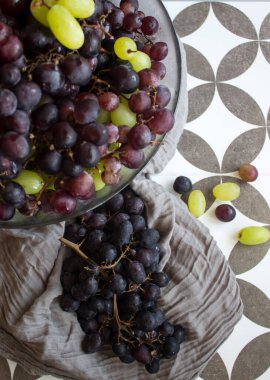 Vazolarda bir sürü üzüm var. Yaz organik meyveleri üst görünüm fotoğrafı. Taze yeşil, siyah ve kırmızı üzümler. Kopyalama alanı olan gri bir arkaplan. Sağlıklı yeme kavramı. 