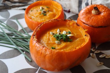 Creamy, nourishing butternut squash soup with a hunk of crusty bread. Fall comfort food. Healthy eating concept. Top view photo of beautiful orange soup served in a squash bowl. 