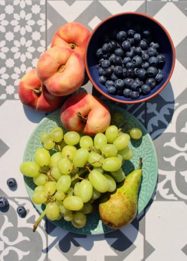 Still life with fruits and berries. Organic berries and fruits on a table. Garden harvest close up photo. Pears, peaches, red currant, blueberry, grapes top view photo. Healthy eating concept. 