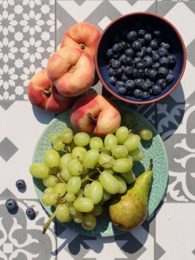Fresh fruits and berries on a table. Top view photo of blueberry, grapes, pears and peaches. Summer food close up photo. Eating fresh concept. 