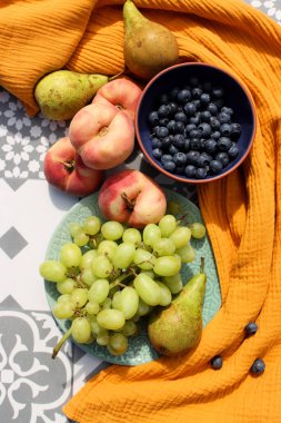 Still life with fruits and berries. Organic berries and fruits on a table. Garden harvest close up photo. Pears, peaches, red currant, blueberry, grapes top view photo. Healthy eating concept. 