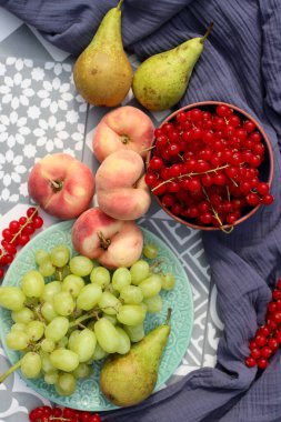 Summer fruits and vegetables on a table. Top view photo of red currant, blueberry, pears, grapes, peaches on blue textured fabric background. Still life with organic fruits. 