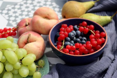 Summer fruits and vegetables on a table. Top view photo of red currant, blueberry, pears, grapes, peaches on blue textured fabric background. Still life with organic fruits. 