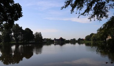 Şehir parkında büyük bir göl, sakin su, mavi gökyüzü, ağaçlar. Hollanda, Waterland 'da Broek. 