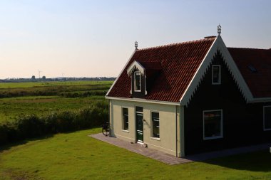 Bir tarlada Hollanda kır evi, beyaz duvarlar, kırmızı kiremitli çatı, yeşil çimenler. Büyük ev, yakın plan fotoğraf. Hollanda 'nın kırsal manzarası. 