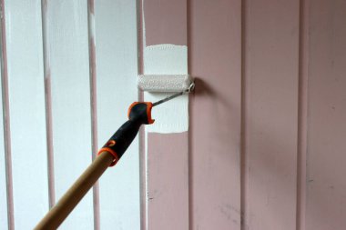 Paten fırçası resmi. Ahşap duvarları beyaz renge boyuyor. Ev yenileme konsepti. Yüzeyde işçi resmi. 
