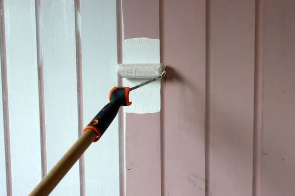 Roller brush painting. Painting wooden walls with white color. Home renovation concept. Worker painting on surface.