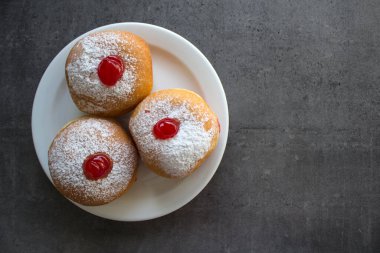 Geleneksel İsrail çörekleri beyaz tabakta. Çilek reçelli çöreklerin en iyi görüntüsü. Gri desenli arka plan ve kopyalama alanı. Hanuka yemeği yakın.. 