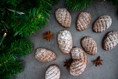 Koyu gri desenli arka planda Noel bisküvileri. Kurabiye, tarçın, anason ve festival dekorasyonlarının en üstteki görüntüsü. 