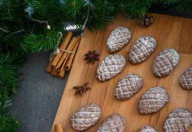 Ahşap arka planda çam kozalağı kurabiyeleri. Çikolatalı bisküviler, tarçın çubukları. Anasonlu yıldız. Noel menüsü fikirleri. 