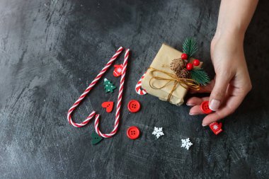 Noel süsleriyle dolu bir hayat. Paketlenmiş bir hediyenin, kırmızı popoların, koyu arkaplanlı baston şekerlerin fotokopi çekilen fotoğrafını çek.. 