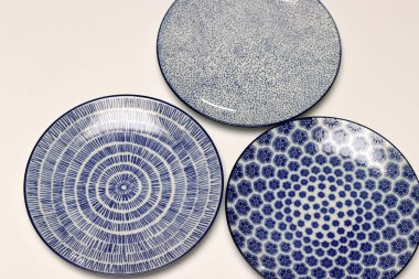 Arka planda mavi seramik tabaklar ve kaseler var. Seramik sofra takımı kapat.