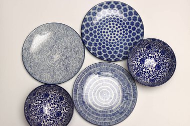 Arka planda mavi seramik tabaklar ve kaseler var. Seramik sofra takımı kapat.