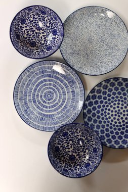 Arka planda mavi seramik tabaklar ve kaseler var. Seramik sofra takımı kapat.