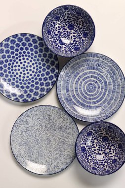 Arka planda mavi seramik tabaklar ve kaseler var. Seramik sofra takımı kapat.