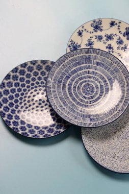 Arka planda mavi seramik tabaklar ve kaseler var. Seramik sofra takımı kapat.