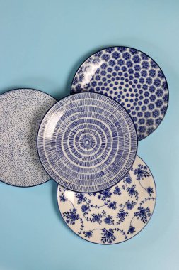 Arka planda mavi seramik tabaklar ve kaseler var. Seramik sofra takımı kapat.
