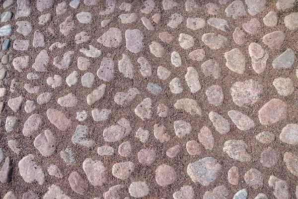 Sand and paving stone road, natural ground surface. Paving stone road somewhere in old part of a city: beautiful cobblestones, neat road pattern, natural daylight, true colors, sharp texture.