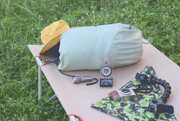 Schlafsack Stoffmatratze Gras Campingausrüstung Wandern Kompass Gelber Hut Und Kamera — Stockfoto