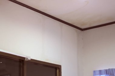 Odanın duvarlarında su akış izleri, kahverengi duvara tahta, pencere perdesine, beyaz duvara, siyah cam odaya.