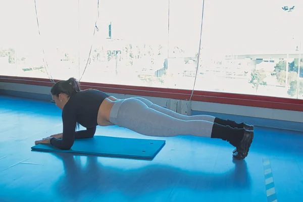 Brunett Kvinna Gör Buken Planka Gymmet Framför Ett Stort Fönster — Stockfoto