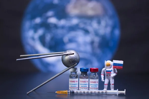 Group of russian vaccines named after a well-known russian satellite against Covid 19 virus with syringe and small astronaut. With background of planet earth and out of focus. Tag text reads, corona virus injection only.