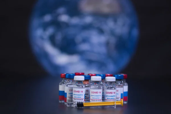 Group of russian vaccines against Covid 19 virus and syringe. With background of planet earth and out of focus. Tag text reads, corona virus injection only.