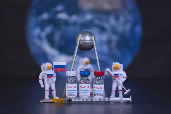 Bir grup Rus aşısı, Covid 19 virüsüne karşı bilinen bir Rus uydusunun küçük bir grup astronot ve şırıngayla isimlendirilmiş hali. Dünya gezegeninin arka planında ve odak dışı. Etiket metni, sadece korona virüsü enjeksiyonu.
