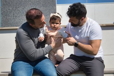 Eşcinsel evli çift açık havada kızlarını çok mutlu oynuyorlar. Aile çeşitliliği.