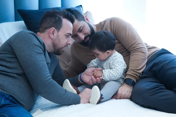 Evlerindeki evlilik yatağında kızlarıyla oynayan eşcinsel bir çift. Aile çeşitliliği.