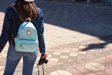 Genç ve güzel Asyalı turist, tatil gezisi sırasında elinde refleks kamerasıyla bir şehir anıtına bakıyor..