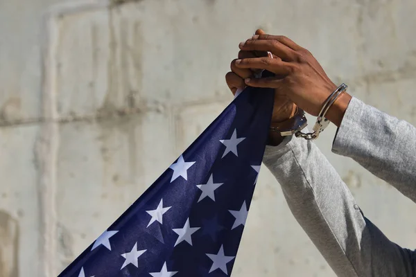 Detail of african american hands in shackles clutching a united states flag. Racial repression.