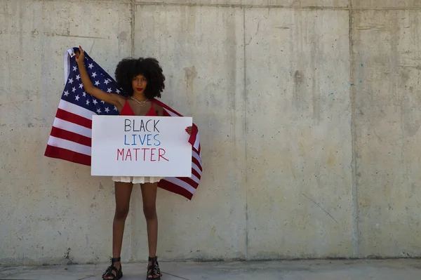 Young and beautiful African-American woman with a United States flag claiming the rights of her community. Black lives matter.