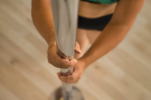 Detail of woman\'s hands gripping a pole dance. Close-up with selective focus.