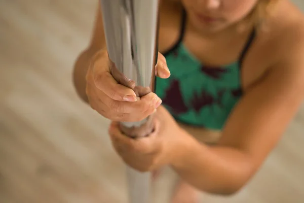 Detail of woman\'s hands gripping a pole dance. Close-up with selective focus.
