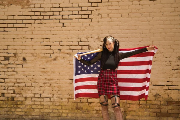 首の後ろに野球のバットと彼女の後ろに米国の旗と彼女の後ろに黄色の壁を背景に — ストック写真