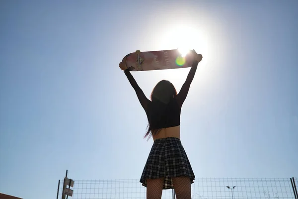 Podsvícení Mladé Dívky Punk Stylu Zvedání Skateboard Nad Hlavou Dívá — Stock fotografie