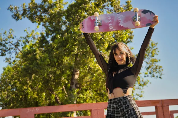 Linda Joven Con Estilo Punk Heterocromía Levantando Monopatín Sobre Cabeza — Foto de Stock