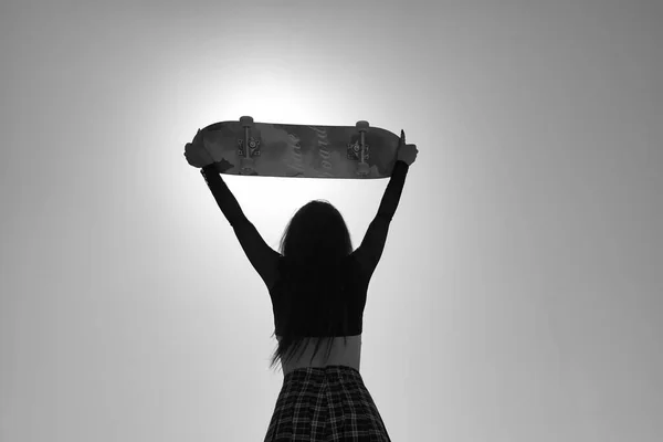 Подсветка Молодой Девушки Панк Стилем Поднимающей Скейтборд Над Головой Глядя — стоковое фото