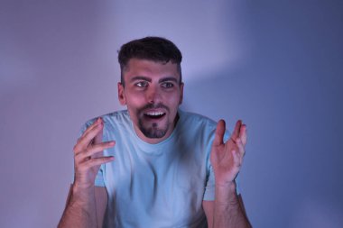 Kollarını açmış, beyaz arka planda şaşkın şaşkın bakan genç İspanyol bir adam..