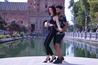 Çok ırklı genç bir çift, dışarıda şehvetle dans ederken figürler yapıyor..