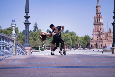 Çok ırklı genç bir çift, dışarıda şehvetle dans ederken figürler yapıyor..